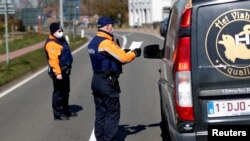 Des policiers belges contrôlant un chauffeur à la frontière belgo-néerlandaise lors du confinement du imposé par le gouvernement belge pour tenter de ralentir la propagation du COVID-19.