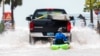 Sebuah truk menarik seorang pria di atas kayak di jalan dataran rendah yang terdampak banjir yang dipicu oleh Badai Ian, di Key West, Florida, Rabu sore, 28 September 2022. (AP/Mary Martin)