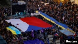 2022 年 10 月 30 日，在捷克共和国布拉格举行的亲政府和反战抗议集会上，示威者举着旗帜。 