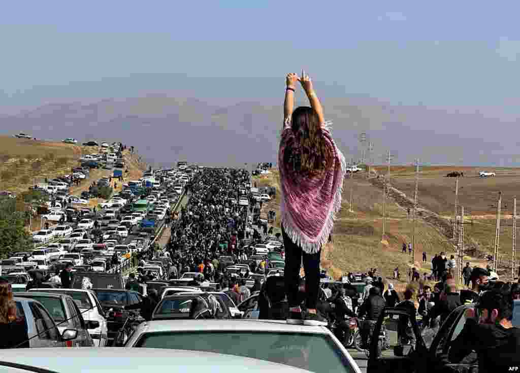 This UGC image posted on Twitter reportedly on Oct. 26, 2022 shows an unveiled woman standing on top of a vehicle as thousands make their way towards Aichi cemetery in Saqez, Mahsa Amini&#39;s home town in the western Iranian province of Kurdistan, to mark 40 days since her death, defying heightened security measures as part of a bloody crackdown on women-led protests.