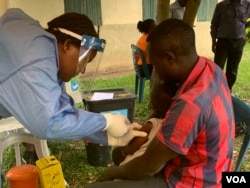 A Father holds his 5 year old daughter as she gets the Ebola trial vaccine in Kasese district Uganda, June 16, 2019. (H. Athumani for VOA)