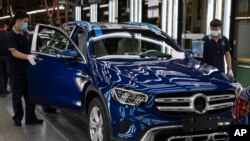 资料照 - 2020年5月在北京的北京奔驰汽车有限公司的汽车装配线上，工人们正在检查装配中的奔驰轿车。