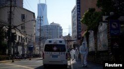 上海街头停着的120急救车旁走过身穿防护服的人。（2022年4月16日)