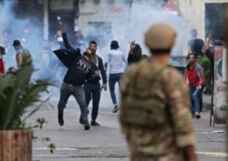 FILE - Lebanese protesters hurl rocks at soldiers as anger over a spiraling economic crisis re-energized a months-old anti-government movement in defiance of a coronavirus lockdown, in the northern port city of Tripoli, April 28, 2020.