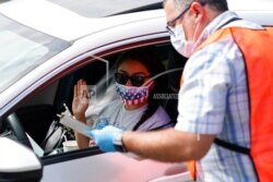 In this June 26, 2020 photo, Vida Kazemi is sworn in as a U.S. citizen by Allen Chrysler, immigration services officer, during a drive-up naturalization ceremony in Laguna Niguel, Calif.