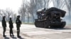 Service members of pro-Russian troops stand next to a combat engineering vehicle, in the southern port of Mariupol, Ukraine, April 20, 2022.