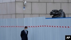 上海一家商场围栏外走过一名戴着口罩的工作人员。（2022年4月20日）