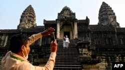 មគ្គុទេសក៍​ទេសចរណ៍​ម្នាក់​ថត​រួប​ឱ្យ​ភ្ញៀវ​ទេសចរ​នៅ​ប្រាសាទ​អង្គរវត្ត​ក្នុង​ខេត្ត​សៀមរាប កាល​ពី​ថ្ងៃ​ទី​៨ ខែ​មេសា ឆ្នាំ​២០២២។