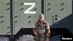 在被俄罗斯围攻的乌克兰港城马里乌波尔,一名亲俄部队成员站在一辆标有Z字符的军车旁.(2020年4月20日)