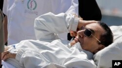 Mantan Presiden Mesir Hosni Mubarak dikawal oleh petugas medis dan tentara saat mendarat dengan helikopter ambulansnya di rumah sakit militer Maadi, seusai mengikuti persidangan di Kairo (13/4).