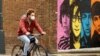 A man wearing a protective mask rides a bike past a mural depicting members of The Beatles, amid the outbreak of the coronavirus disease, in Liverpool, Britain, Oct. 13, 2020. 