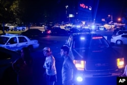 Bystanders look on as emergency personnel respond to the scene of a deadly shooting at the Grand Theatre in Lafayette, La., Thursday, July 23, 2015.