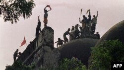 
(FILES) Hindu fundamentalists shout and wave banners as they stand atop a stone wall as they celebrate the destruction of the 16th Century Babri Mosque at a disputed holy site in the city of Ayodhya on December 6, 1992.