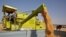 FILE - A combine deposits harvested wheat in a tractor trolley at a field on the outskirts of Ahmedabad, India, March 16, 2022.