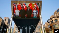 19일 중국 베이징 거리에서 김정은 북한 국무위원장 부부와 시진핑 중국 국가주석과 부인 펑리위안 여사가 인민대회당에서 열린 공식 환영식에 참석한 모습이 대형 TV 화면에 중계되고 있다. 