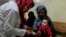 An Afghan woman holds her sick daughter as a nurse treats her in the malnutrition ward of the Indira Gandhi Children's Hospital in Kabul, Afghanistan, Feb. 24, 2022. 