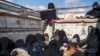 Women and children fleeing from the last Islamic State group's tiny pocket in Syria sit in the back of a truck near Baghuz, eastern Syria, Feb. 11, 2019. 