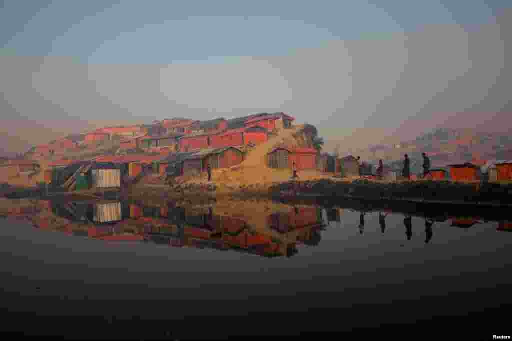 Rohingya refugees walk by a pond at the Balukhali refugee camp near Cox&#39;s Bazar, Bangladesh.
