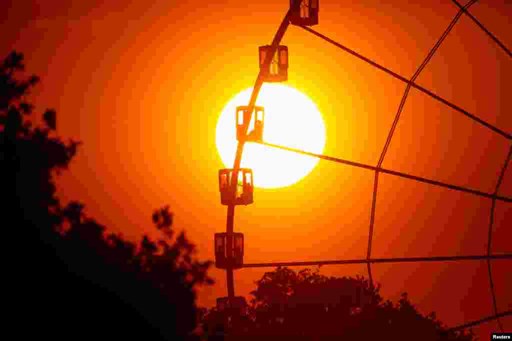 The setting sun is seen through the giant Ferris wheel at Place de la Concorde, in Paris, France, May 8, 2018.