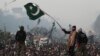 A supporter of Tahir-ul Qadri waves a Pakistani flag as he walks on a container on the third day of protests in Islamabad, Pakistan, January 16, 2013.