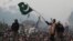 A supporter of Tahir-ul Qadri waves a Pakistani flag as he walks on a container on the third day of protests in Islamabad, Pakistan, January 16, 2013.
