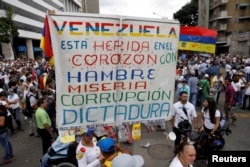 "Venesuela ürəyindən aclıq, səfalət, korrupsiya və diktatura yarası alıb" - Dünyanın ən zəngin neft yataqlarına malik Venesuelada müxalifət fəallarının əllərində tutduğu şüar. Karakas, Venesuela, 10 may, 2017. Təxmin edilir ki, yarıtmaz dövlət siyasətinin doğurduğu aclıq nəticəsində orta venesuelalı 2017-ci ildə 11 kiloqram çəki itirib.