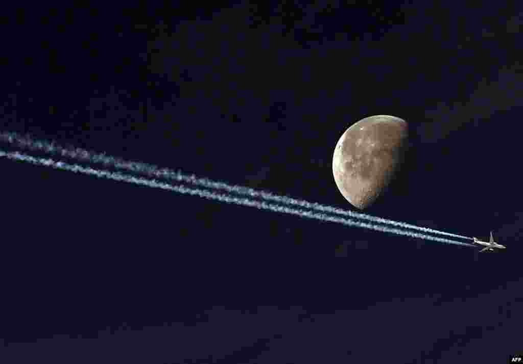A jetliner leaves a vapour trail as it passes in front of the moon in this photo taken from the Algerian capital Algiers.