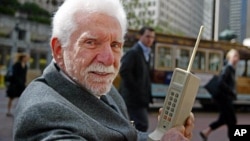 Martin Cooper, difoto pada 2003, memegang model asli prototipe telepon yang ia pakai untuk membuat panggilan telepon pertama dari telepon selular pada 1973. (AP/Eric Risberg)