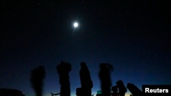Bulan purnama bersinar di atas sekelompok orang yang sedang memburu UFO di padang pasir di luar Sedona, Arizona, 14 Februari 2013. (Foto: Mike Blake/Reuters)