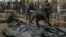 Cemetery employees and police investigators work with bodies of civilians collected from streets and brought to a local cemetery, in the town of Bucha, outside Kyiv, Ukraine April 6, 2022.