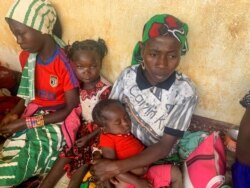 FILE - A woman who fled the violent rebellion in Central African Republic (CAR) sits with her family as they await their registration process, in the border town of Garoua-Boulai, Cameroon, Jan. 7, 2021.