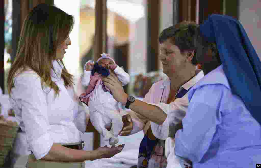 First lady Melania Trump is handed a baby as she visits the Nest Orphanage in Limuru, Kenya, Oct. 5, 2018.