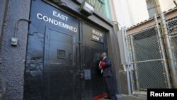 FILE - Lieutenant Sam Robinson, a public information officer at San Quentin State Prison, knocks on the door to the East Block for condemned prisoners during a media tour of California's Death Row in San Quentin, Dec. 29, 2015. 