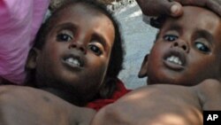Two Somali children suffering from malnutrition lie at a camp for internally displaced people near Mogadishu airport, July 18, 2011.