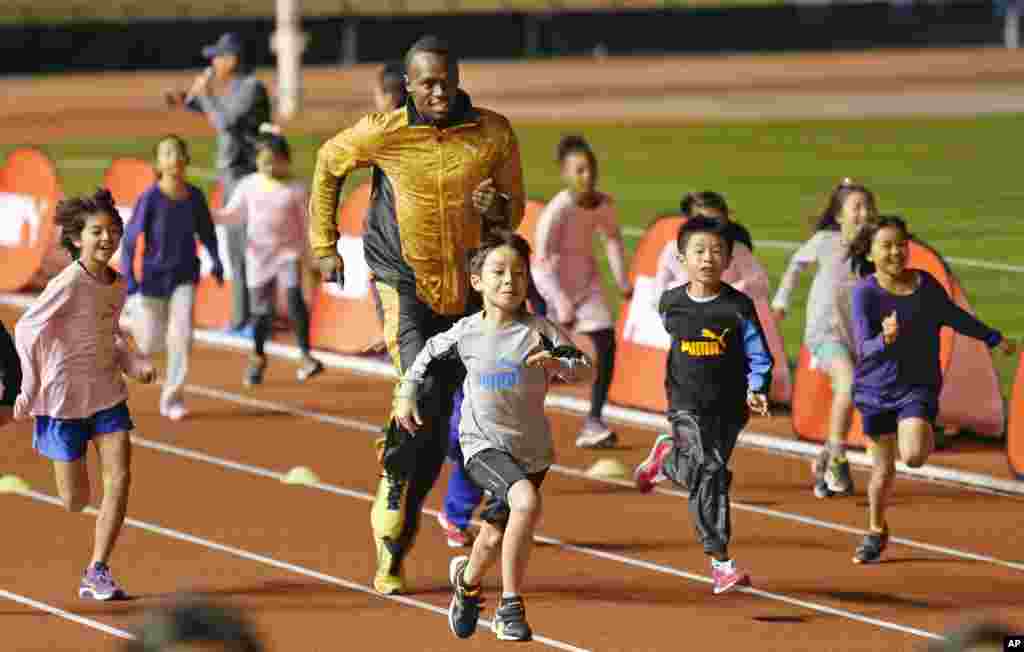 Peraih medali emas olimpiade Usain Bolt dari Jamaika &quot;berkompetisi&quot; dengan anak-anak dalam acara &quot;Klinik Atletik&quot; di Stadion Nasional di Tokyo, Jepang. 