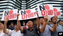 South Korean protesters hold up cards during a rally against Japan in front of a building that houses the Japanese embassy in Seoul, South Korea, Aug. 2, 2019. The signs read " Japanese Prime Minister Shinzo Abe."