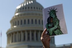 FILE - An activist holds up a pro-refugee image during a demonstration outside the U.S. Capitol in Washington, Oct. 15, 2019.