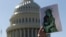 FILE - An activist holds up a pro-refugee image during a demonstration outside the U.S. Capitol in Washington, Oct. 15, 2019.