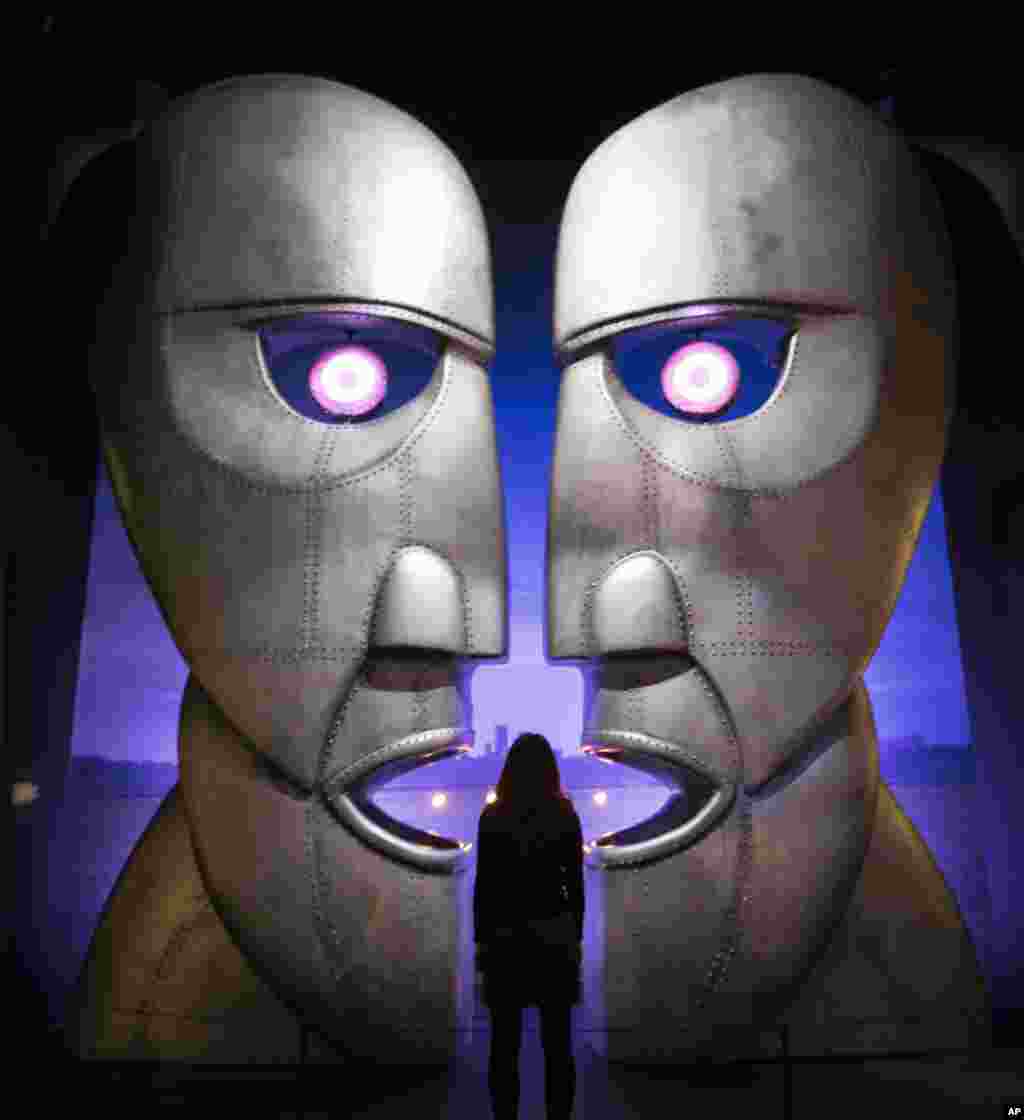 A museum worker poses in front of the metal heads from the rock band Pink Floyd's "Division Bell" album at the band's exhibition, "Their Mortal Remains" at the V&A museum in west London.