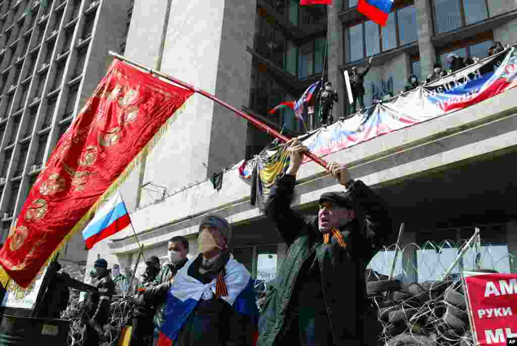 Para aktivis pro-Rusia mengibarkan bendera Soviet dan Rusia di kota Donetsk, Ukraina timur menuntut referendum untuk bergabung dengan Rusia.