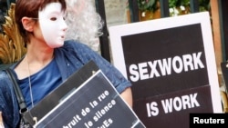一名戴着面具的妓女举着标语牌参加示威,抗议法国里昂取缔卖淫提案。（2012年7月6日）