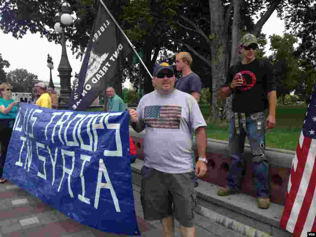 反对美国军事干预叙利亚的抗议人士向路过的行人与车辆展示抗议标语。