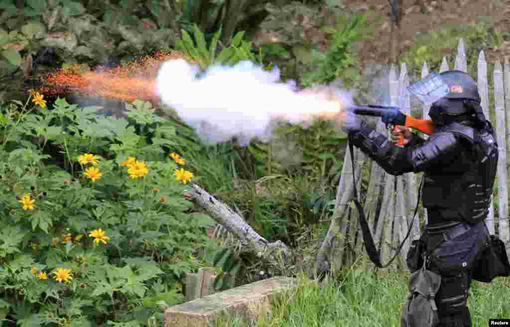 Seorang polisi anti huru-hara menembakkan gas air mata ke para demonstran masyarakat adat yang memblokir jalan toll Pan Amerika di Mondomo, Kolombia, 17 Oktober 2013. Ratusan masyarakat adat memblokir jalan toll Pan Amerika antara Cali dan Popayan, menuntut ditegakkannya perjanjian tertentu yang mereka katakan tidak dipenuhi oleh pemerintah, seperti hak kepemilikan tanah, reformasi kesehatan dan pendidikan, seperti dilaporkan oleh media setempat.