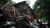 Seorang pria menyelamatkan barang miliknya di sebuah rumah yang rusak akibat gempa bumi di Lumajang, Jawa Timur, 11 April 2021. (Foto: Antara/Zabur Karuru via REUTERS)