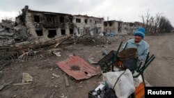 A woman pushes a trolley with her belongings along a street in the separatist-controlled town of Volnovakha in the Donetsk region, Ukraine, March 15, 2022. (REUTERS/Alexander Ermochenko/File Photo)