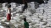 A worker passes a sack of rice to other workers inside a National Food Authority (NFA) warehouse in Taguig City, south of Manila, the Philippines, March 26, 2012. 