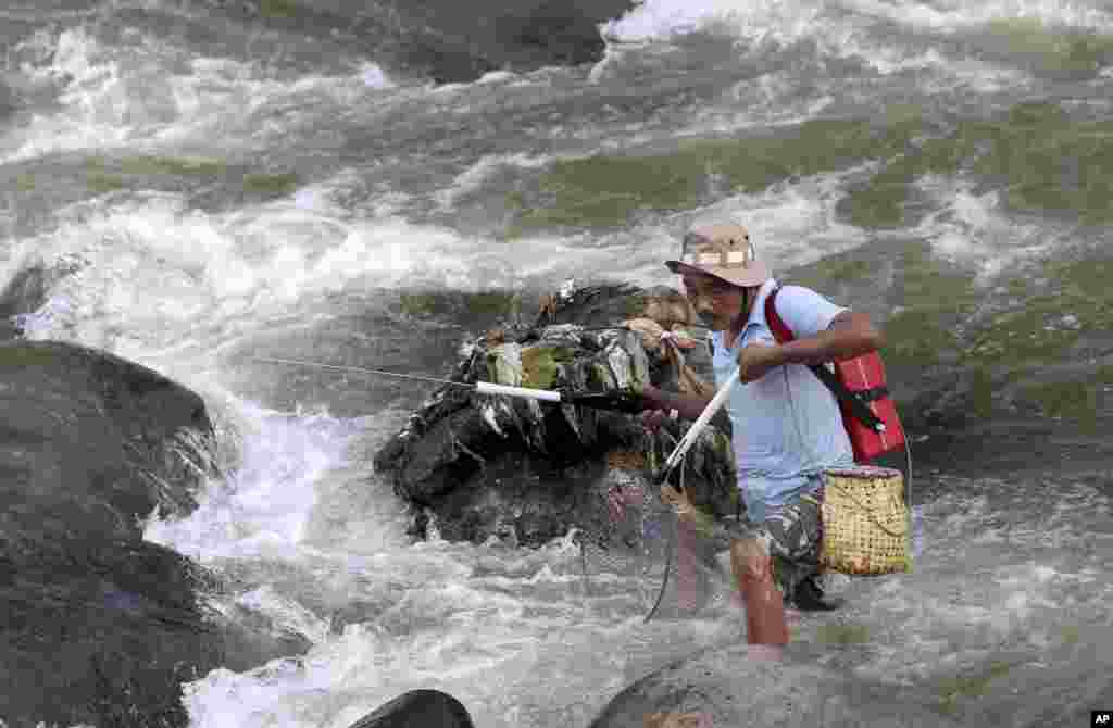 Seorang pria mencari ikan di sebuah sungai di Bogor, Jawa Barat.