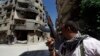 A Shi'ite fighter holds his weapon while patrolling a road at Sayeda Zainab area in Damascus, May 26, 2013.