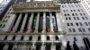 FILE - People walk past the New York Stock Exchange in New York's Financial District, on March 23, 2021. 