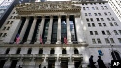 FILE - People walk past the New York Stock Exchange in New York's Financial District, on March 23, 2021. 